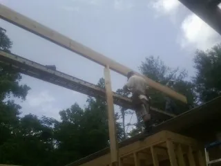 Carpenter setting a ridge beam over a new addition frame — Ice Dam Removal by Roofing Brothers in Westover