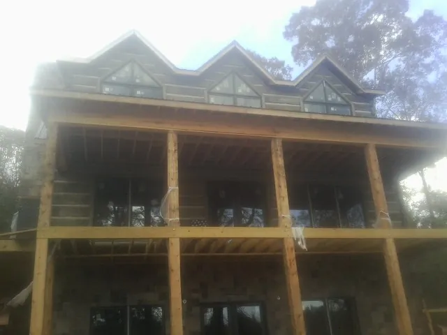 Dormers and porch framing on a large log home under construction — Roof Coating work by our crew in Westover